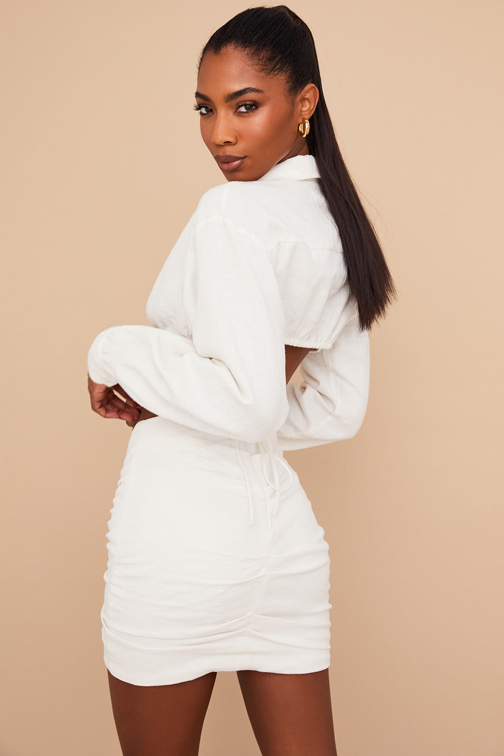 Blouse cropped blanche cassée élégante associée à une mini-jupe taille haute tendance.