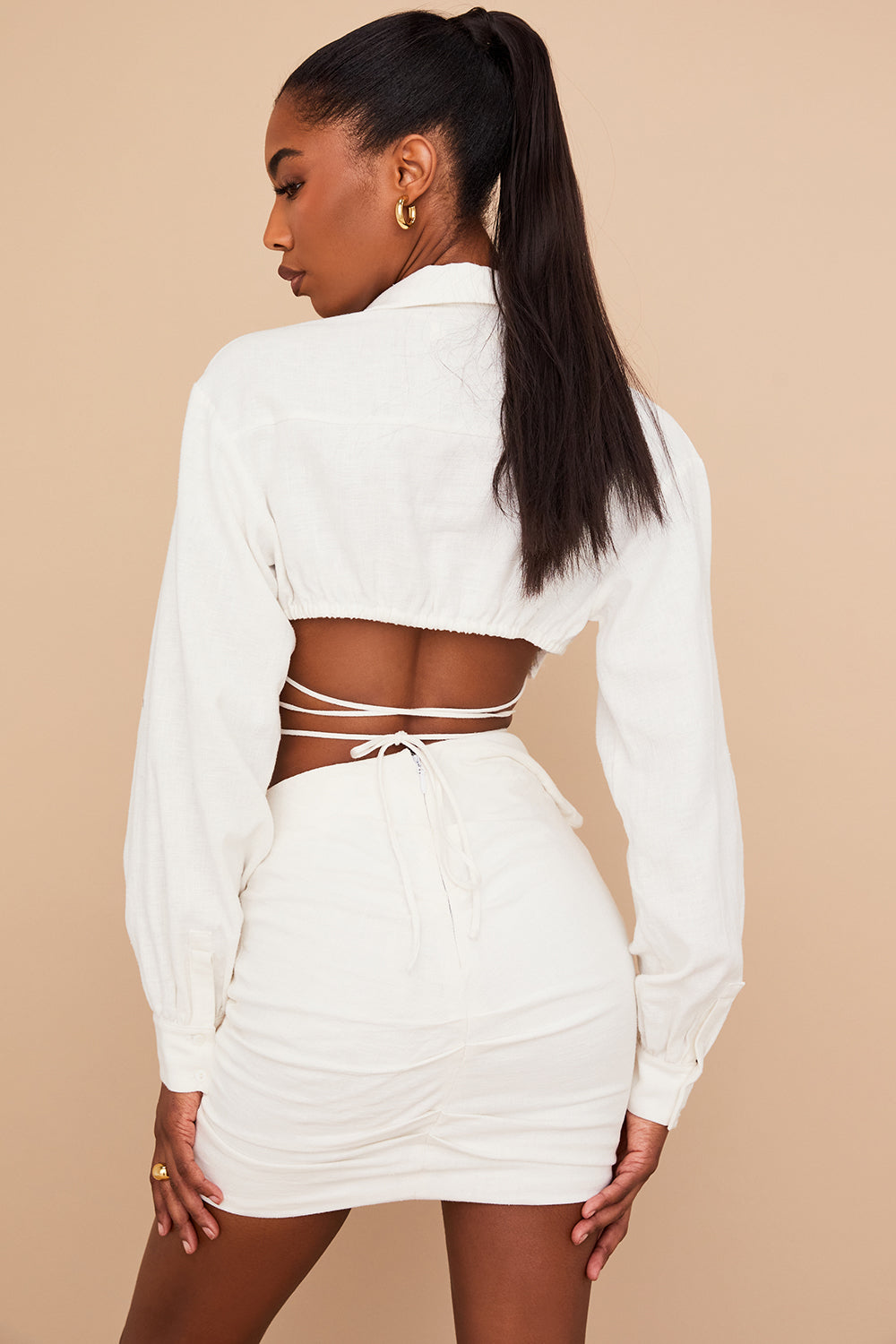 Blouse cropped blanche cassée élégante associée à une mini-jupe taille haute tendance.