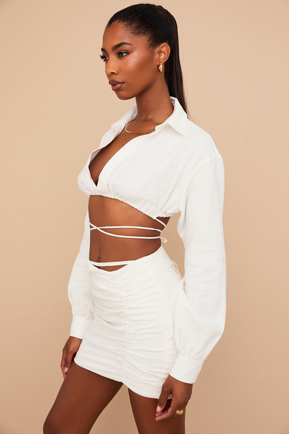 Blouse cropped blanche cassée élégante associée à une mini-jupe taille haute tendance.