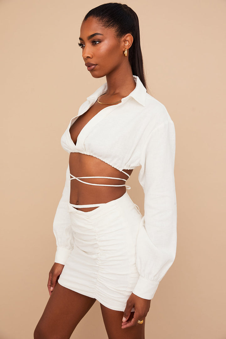 Blouse cropped blanche cassée élégante associée à une mini-jupe taille haute tendance.